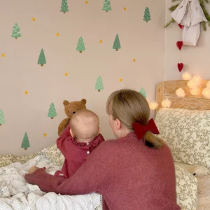 Barn der sidder på sengen og peger på vægdekoration med jule- og naturmotiver.