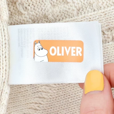 Personlig navnelapp med tegneseriefigur Mumi og Mumitroldene og teksten OLIVER på beige striktrøje.