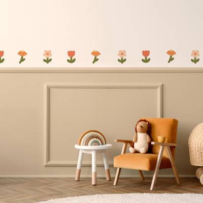 Vægdekoration med blomsterdesign i bløde farver på væggen over en hyggelig stol i et børneværelse.