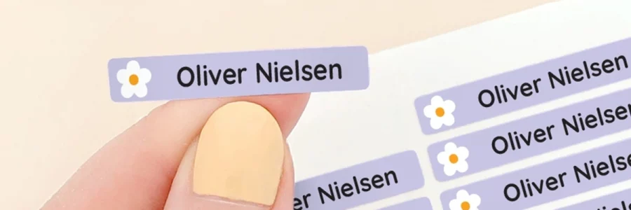 Navnelapper i forskellige farver med personliggørelse, vist med navnet Oliver Nielsen samt blomsterdesign. Ideelt til brug på ting i børns hverdag, såsom madpakker og tøj. Perfekt til at holde styr på ejendele og gøre hverdagens aktiviteter lettere.